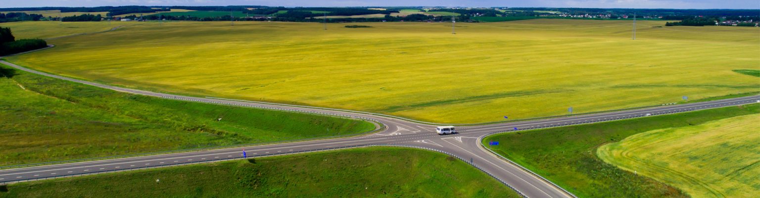 Small bus driving pass a countryside cross junction